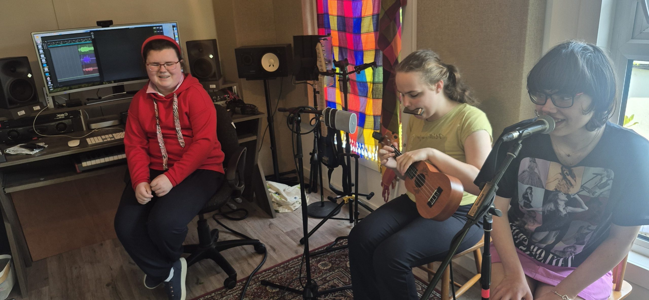 three students playing and mixing music in a home studio