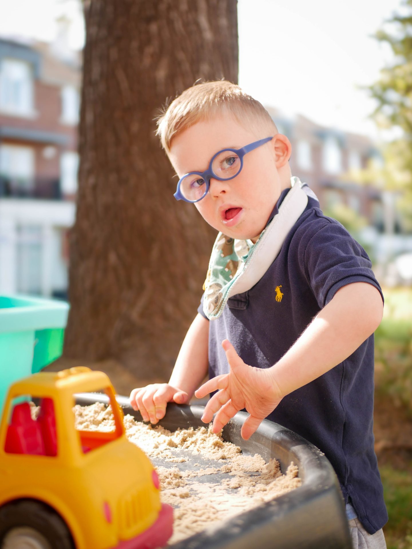 photo of young boy playing with sand and truck